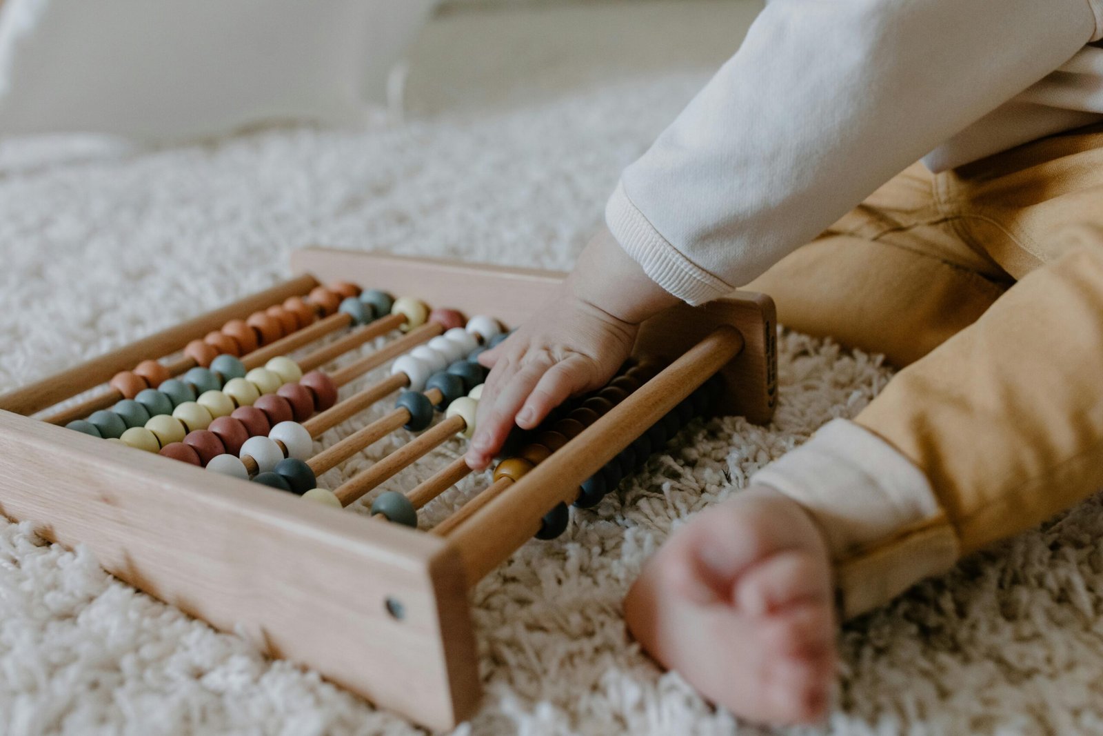 Toddler engaging with a wooden abacus on a fluffy carpet, promoting early learning.